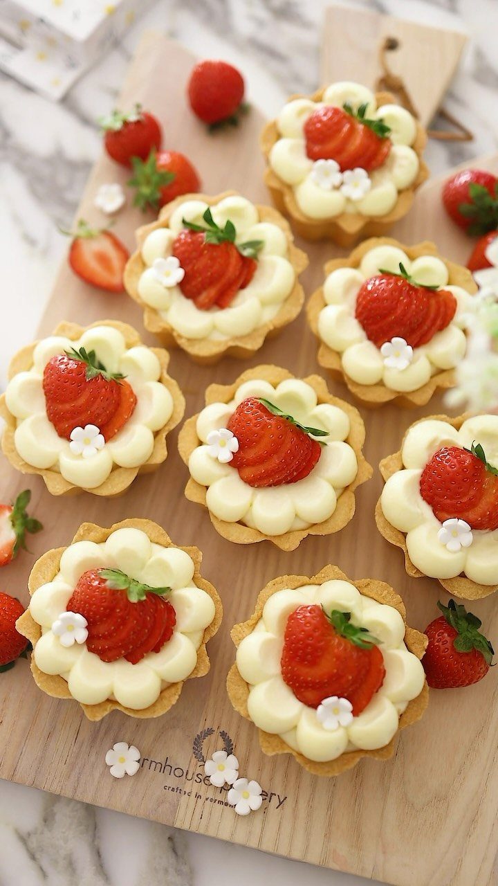 27 Easy Sweet Treats No Bake Ideas, From Fudge to Eton Mess 26 Strawberry tartlets with white cream filling on a light wooden serving board.