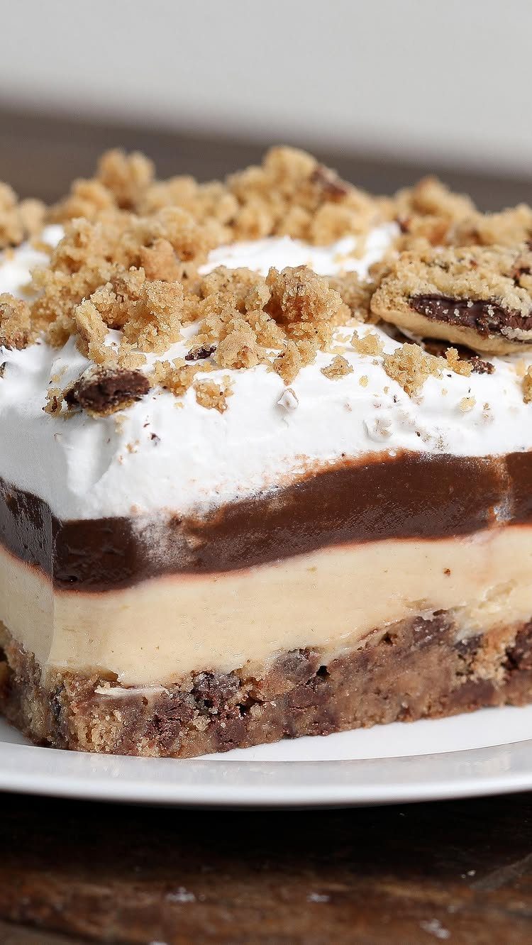 27 Easy Sweet Treats No Bake Ideas, From Fudge to Eton Mess 5 Layered peanut butter pie slice with chocolate and whipped cream topped with cookie crumbles.