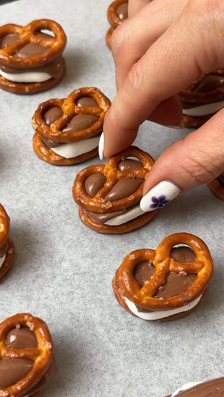 27 Easy Sweet Treats No Bake Ideas, From Fudge to Eton Mess 7 Pretzel s'mores treats with chocolate and marshmallow layers on a parchment surface.