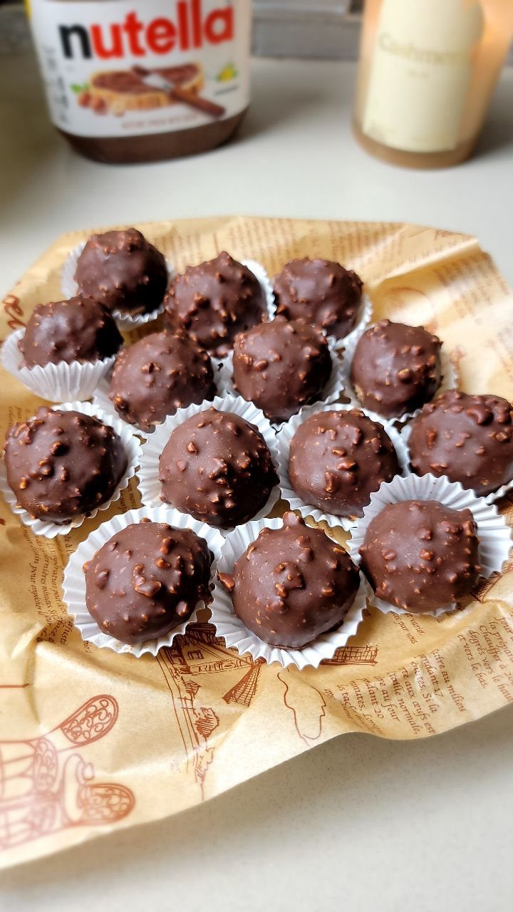 27 Easy Sweet Treats No Bake Ideas, From Fudge to Eton Mess 6 Chocolate truffles with nut pieces in white paper liners on brown parchment paper.