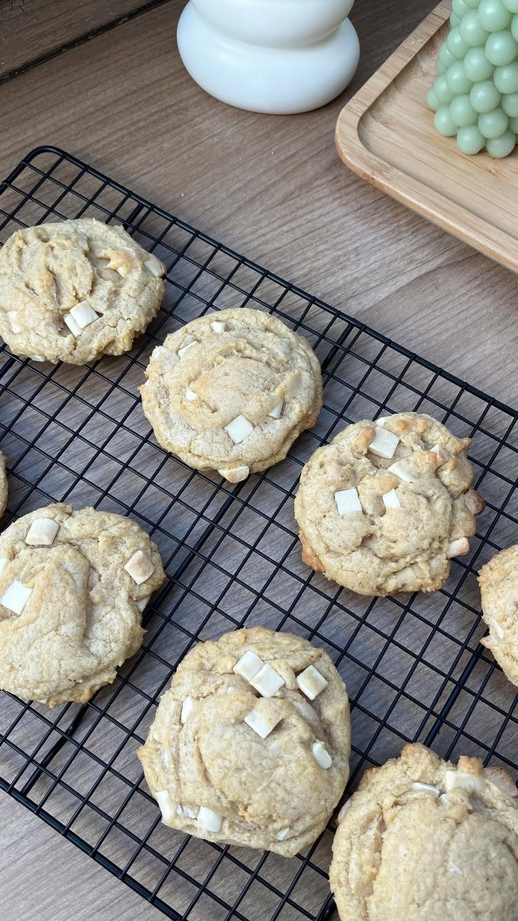 White chocolate chip cookies cooling on a black wire rack on a wooden table.