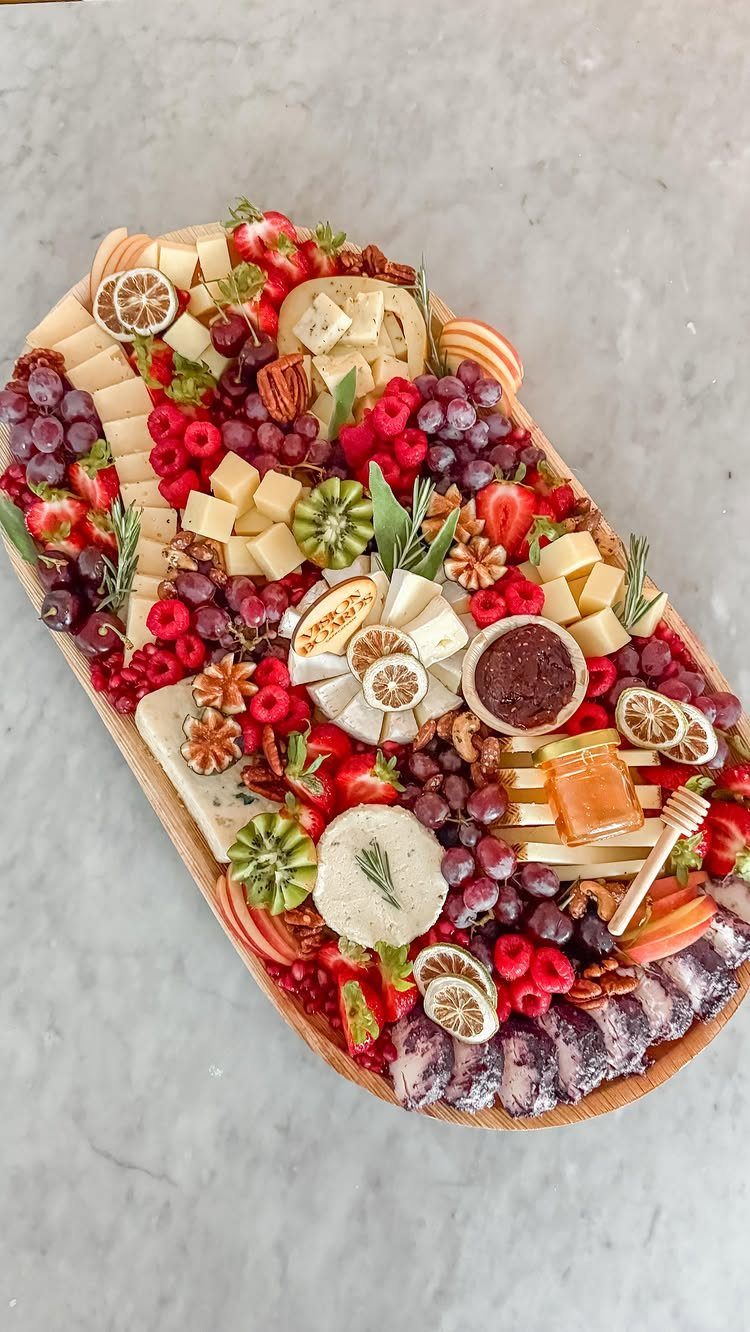 Fruit and cheese platter garnished with fresh rosemary sprigs on a grey background.