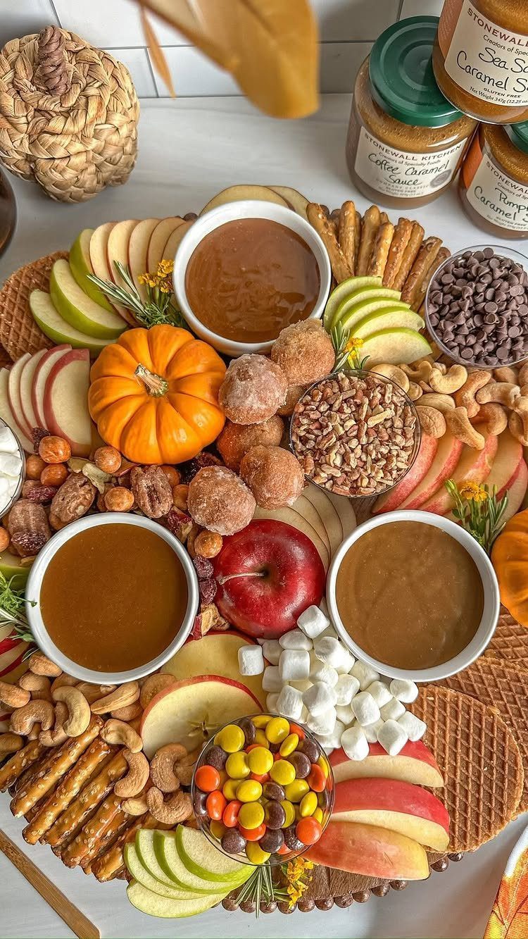 Fall fruit tray with sliced apples, a small pumpkin, caramel dip, and assorted snacks.