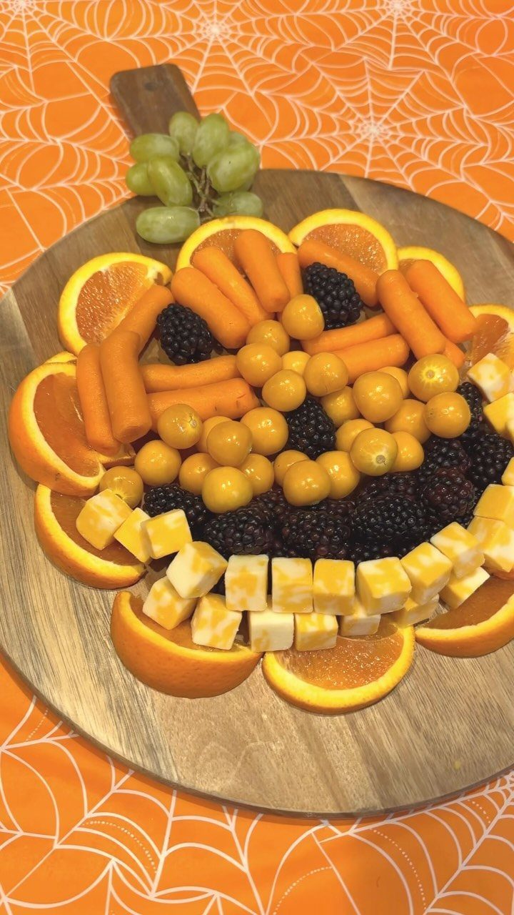 Fruit and vegetable platter arranged in a wreath shape on a wooden board.