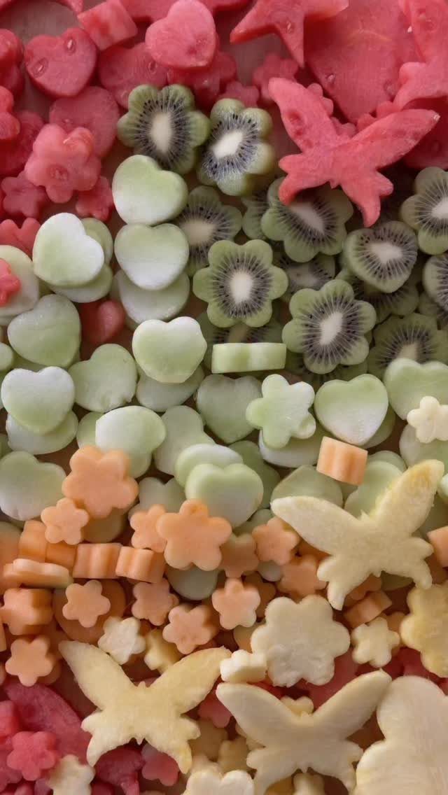 Fruit cut into heart, flower, and butterfly shapes in red, green, and orange.