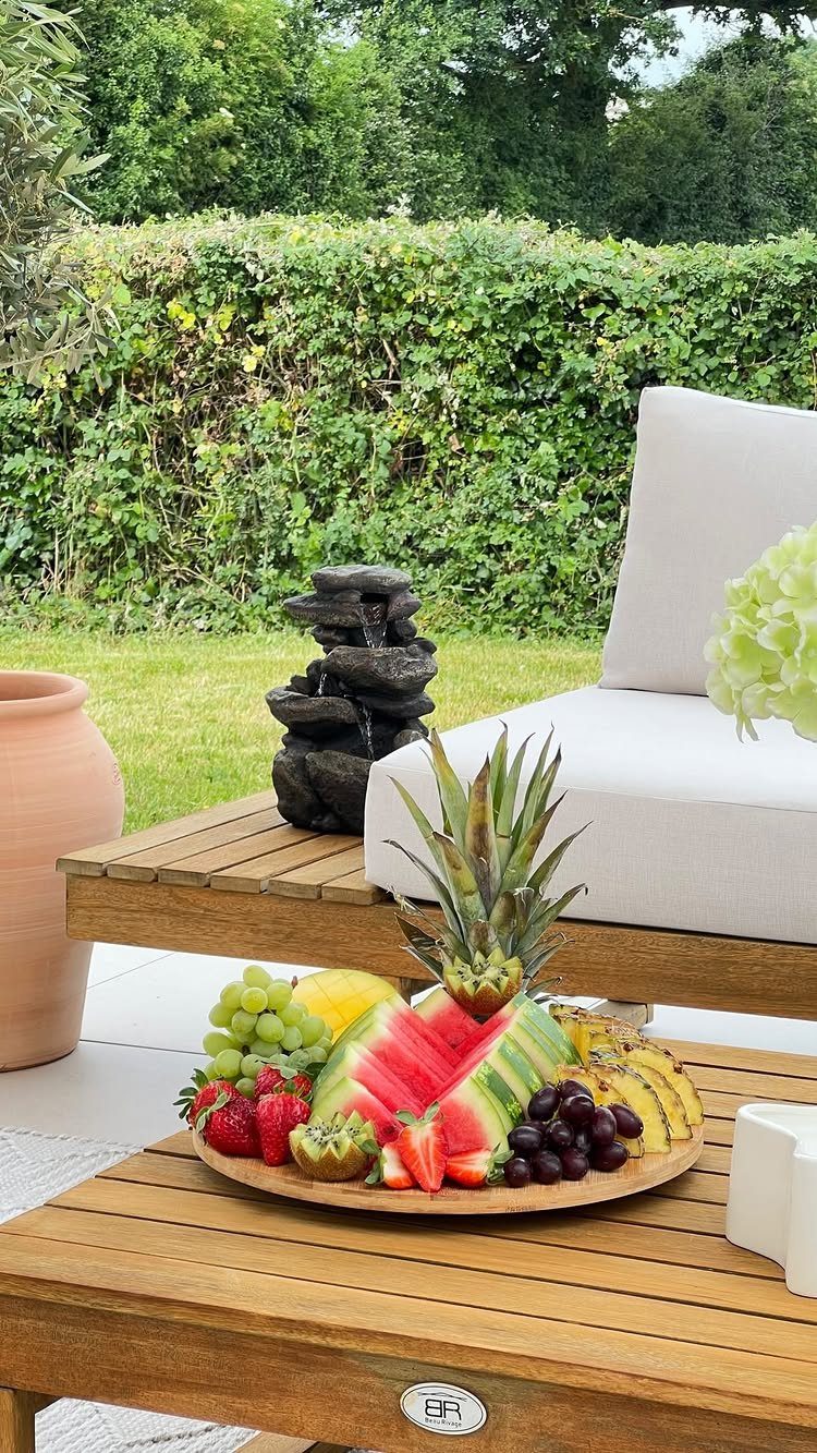 Fruit platter with watermelon wedges, pineapple, and berries on a wooden outdoor table.