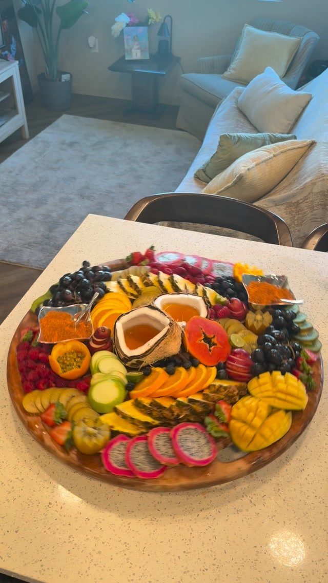Fruit platter with dragon fruit, mango, and a coconut shell dip on a counter.