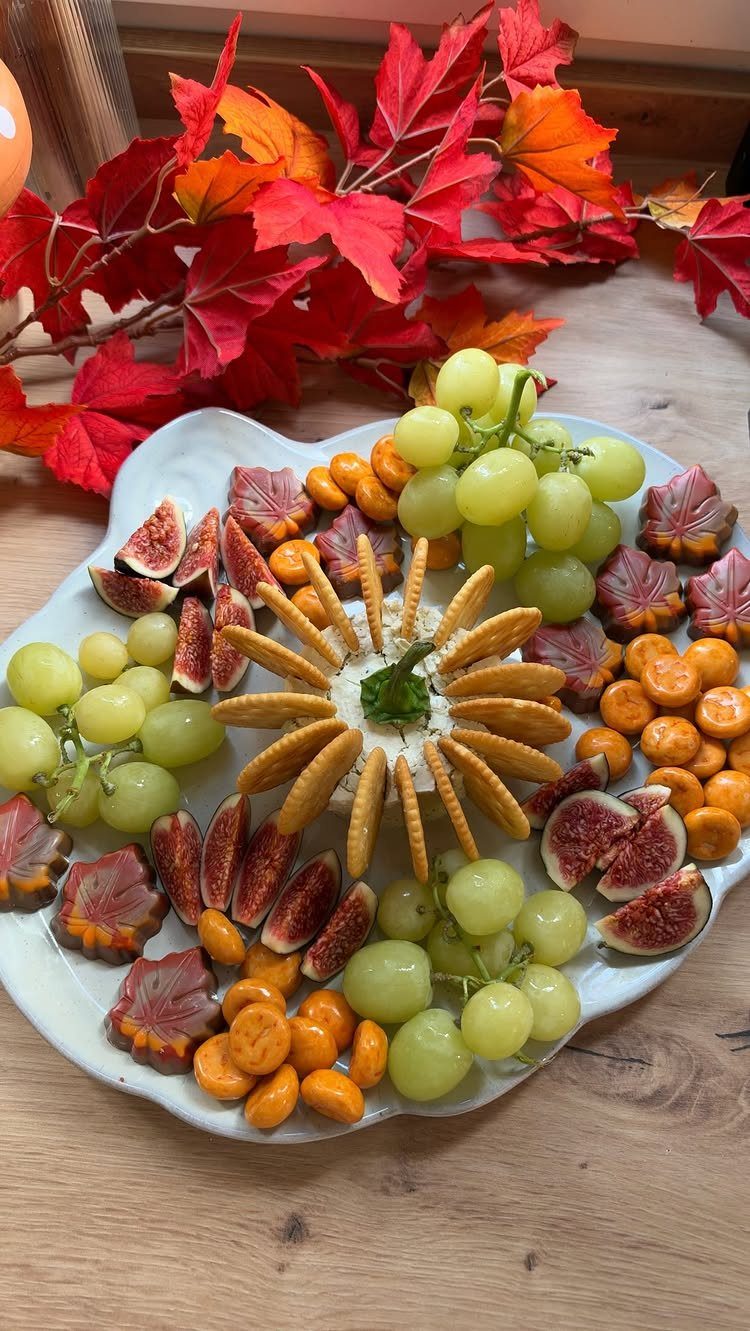 Fruit tray with grapes, figs, and cape gooseberries accented by autumn maple leaves.