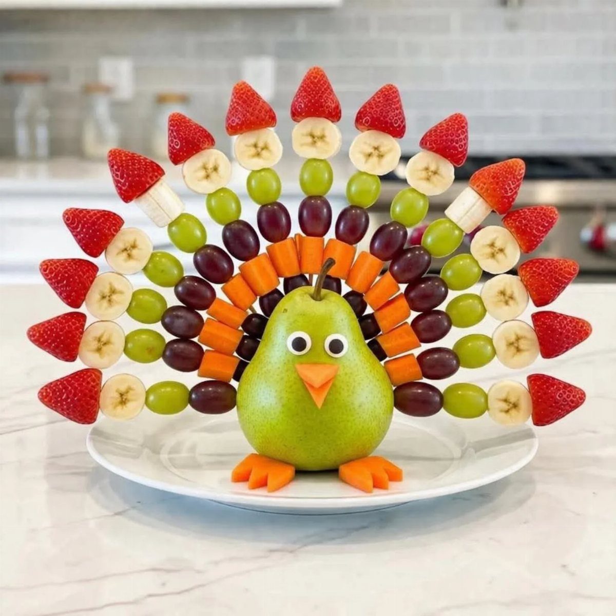 Fruit platter arranged as a turkey with a pear body and strawberry feathers.