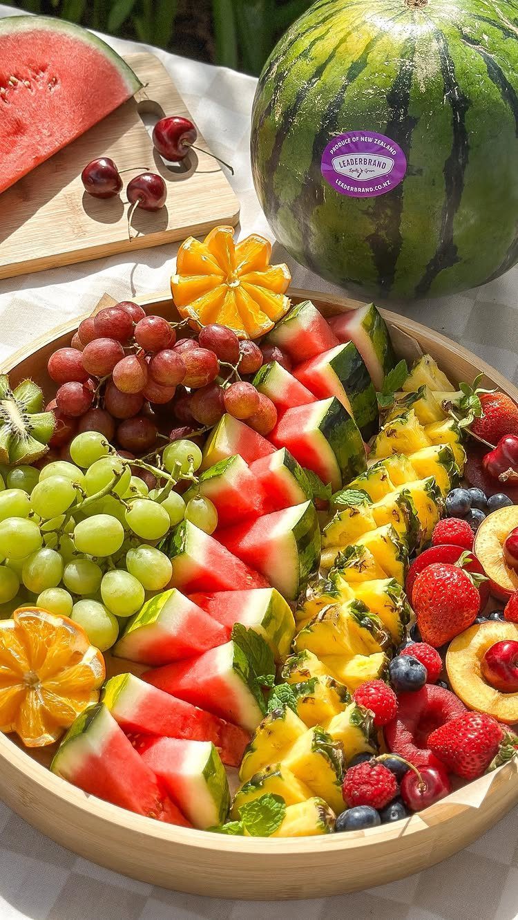 Assorted fresh fruit platter with watermelon, pineapple, grapes, and berries in a wooden bowl