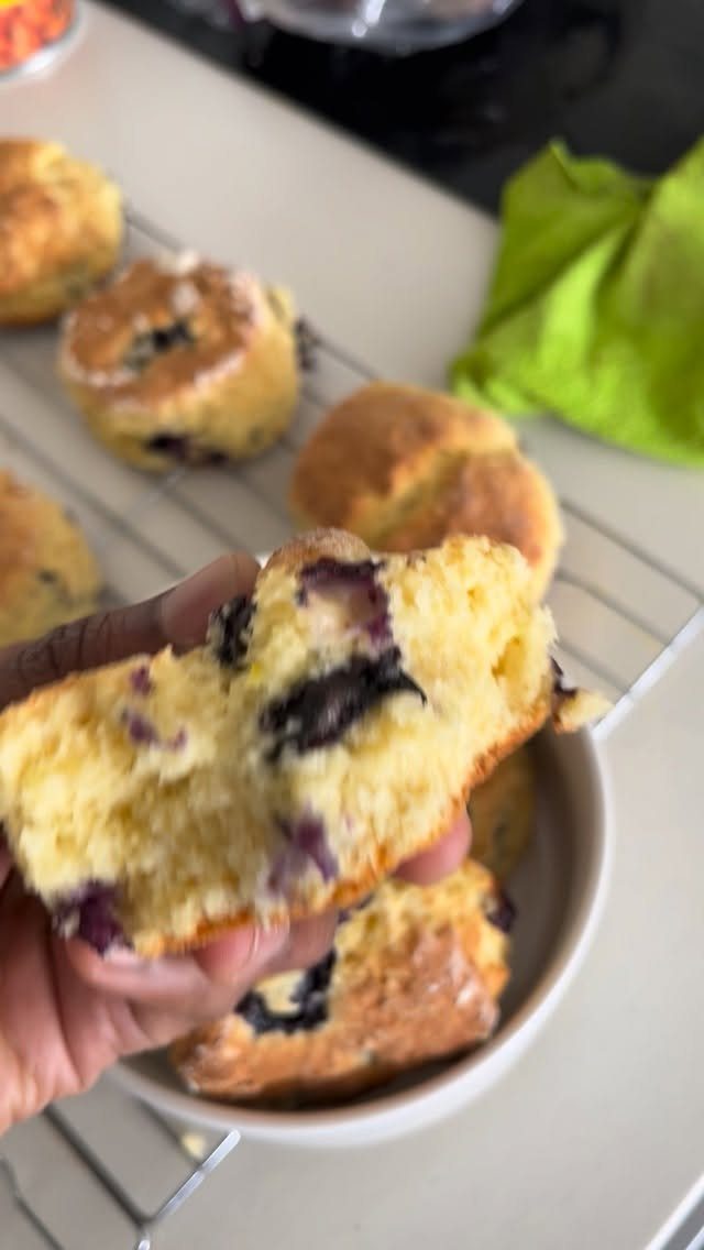 Blueberry scone held open to show interior, with more scones on a rack.