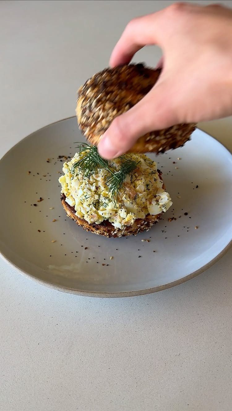 40 Food Lunch Recipes You Can Make in Minutes 3 Egg salad on a seeded bagel with fresh dill on a white plate.