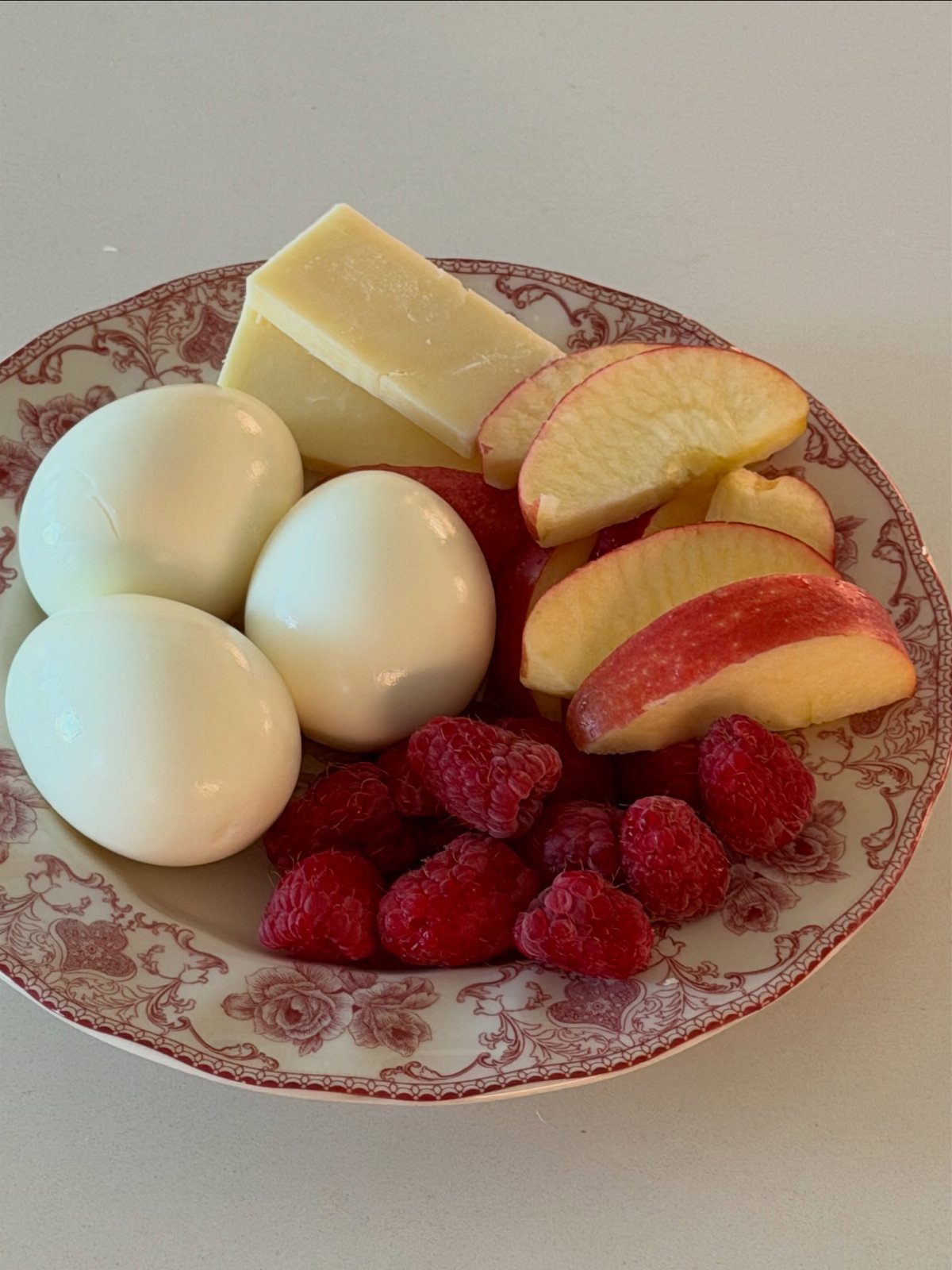 40 Food Lunch Recipes You Can Make in Minutes 2 Hard-boiled eggs, apple slices, raspberries, and cheese on a red floral plate.