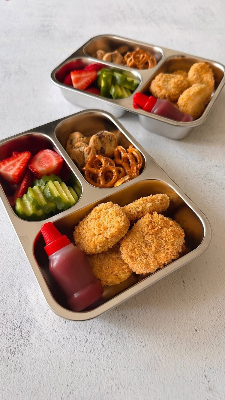 40 Food Lunch Recipes You Can Make in Minutes 19 Two stainless steel bento boxes filled with chicken nuggets, fruit, vegetables, and pretzels.