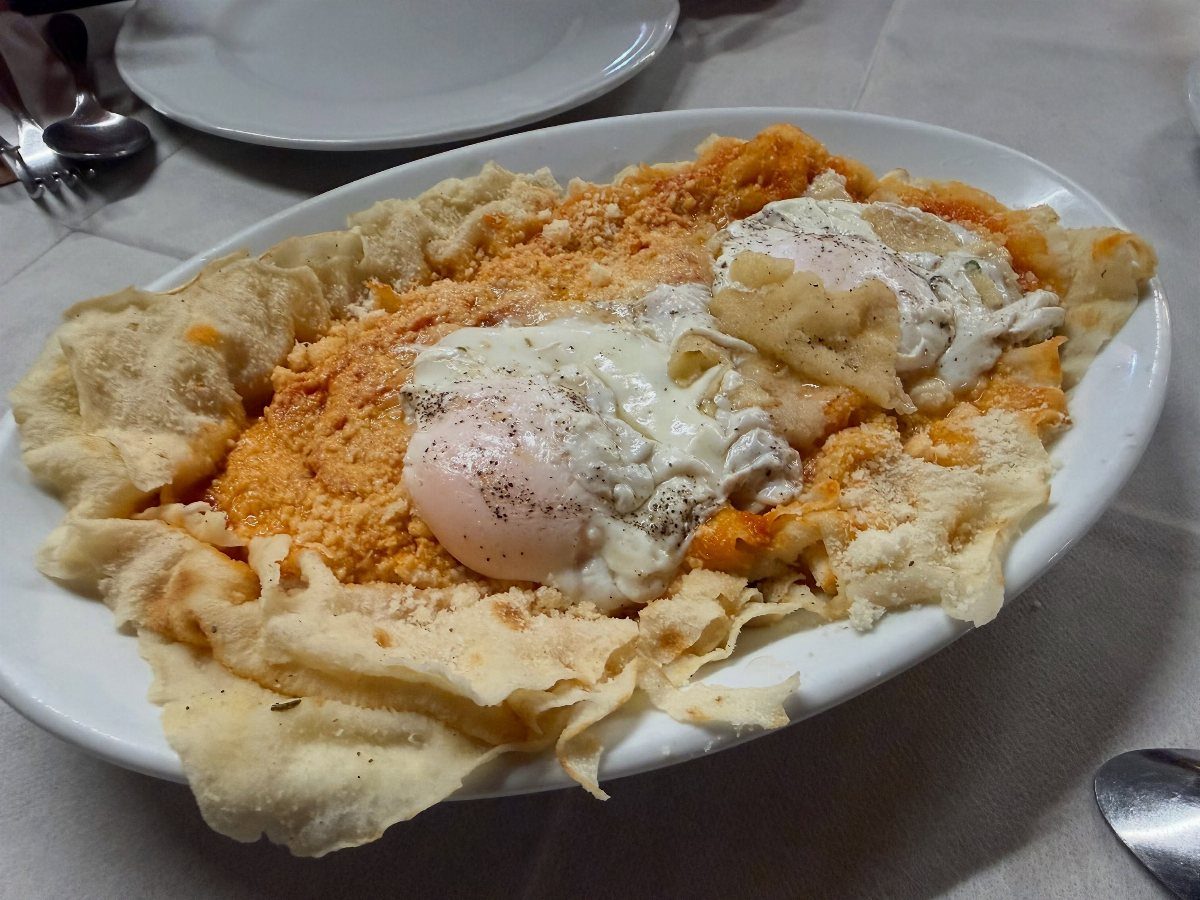 Pane Frattau crisp Sardinian bread with melted cheese and tomato sauce on a platter