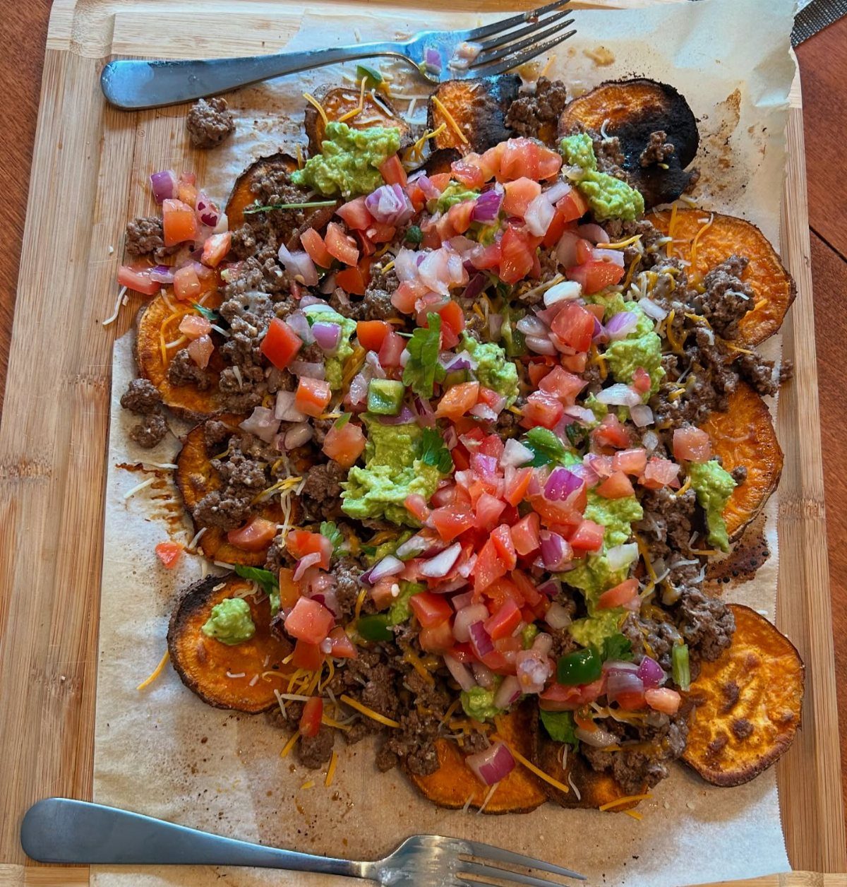 Sweet potato nachos topped with ground meat, guacamole, and fresh tomato salsa.