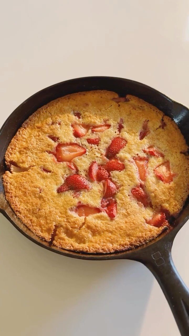 Strawberry cobbler with a golden crust baked in a black cast-iron skillet.