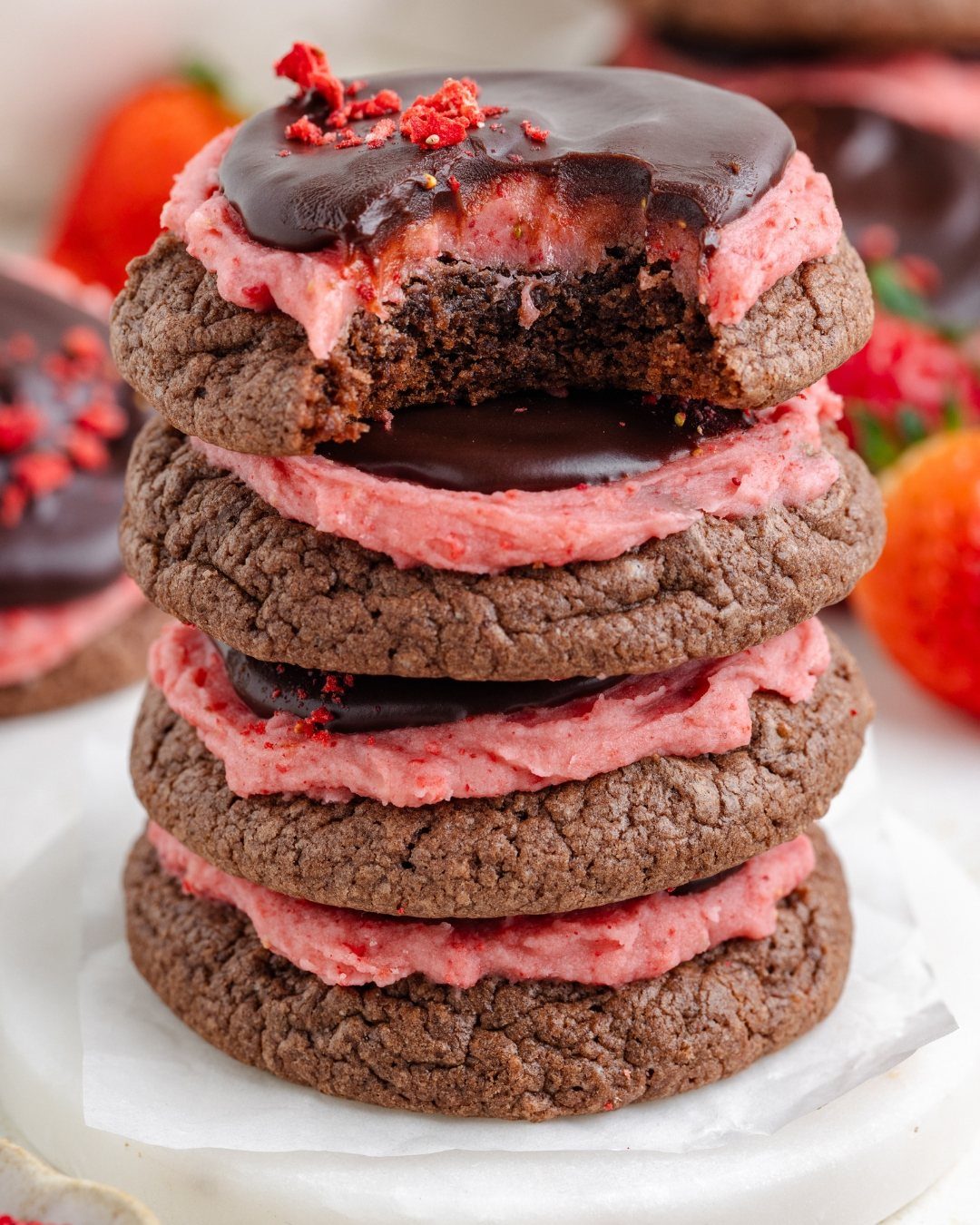 Stacked chocolate cookies with pink strawberry cream filling and dark chocolate glaze topping.
