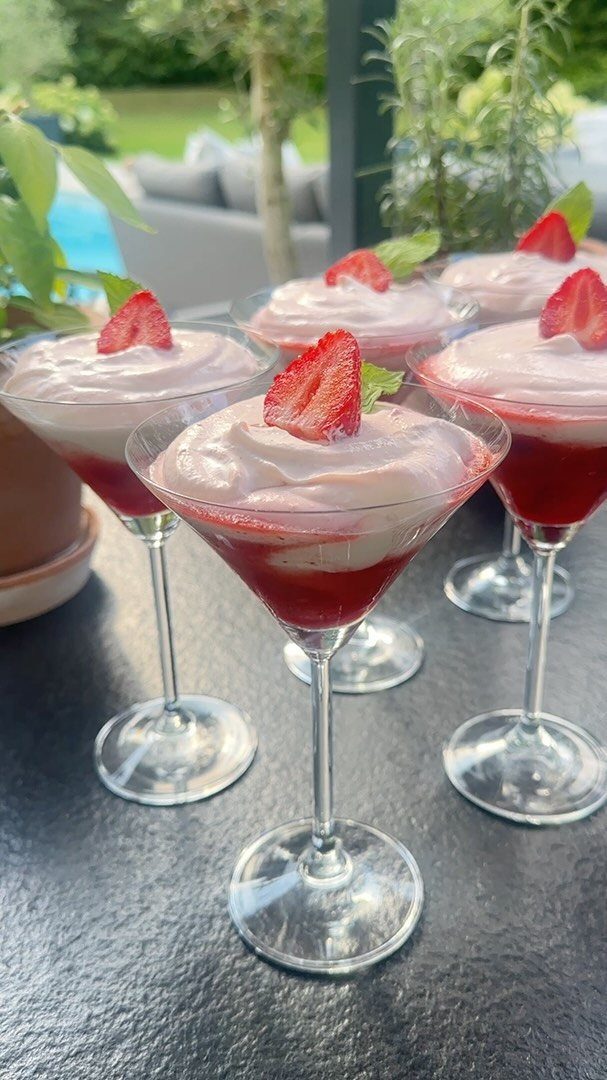 Strawberry fool dessert layered in martini glasses topped with fresh strawberry slices.