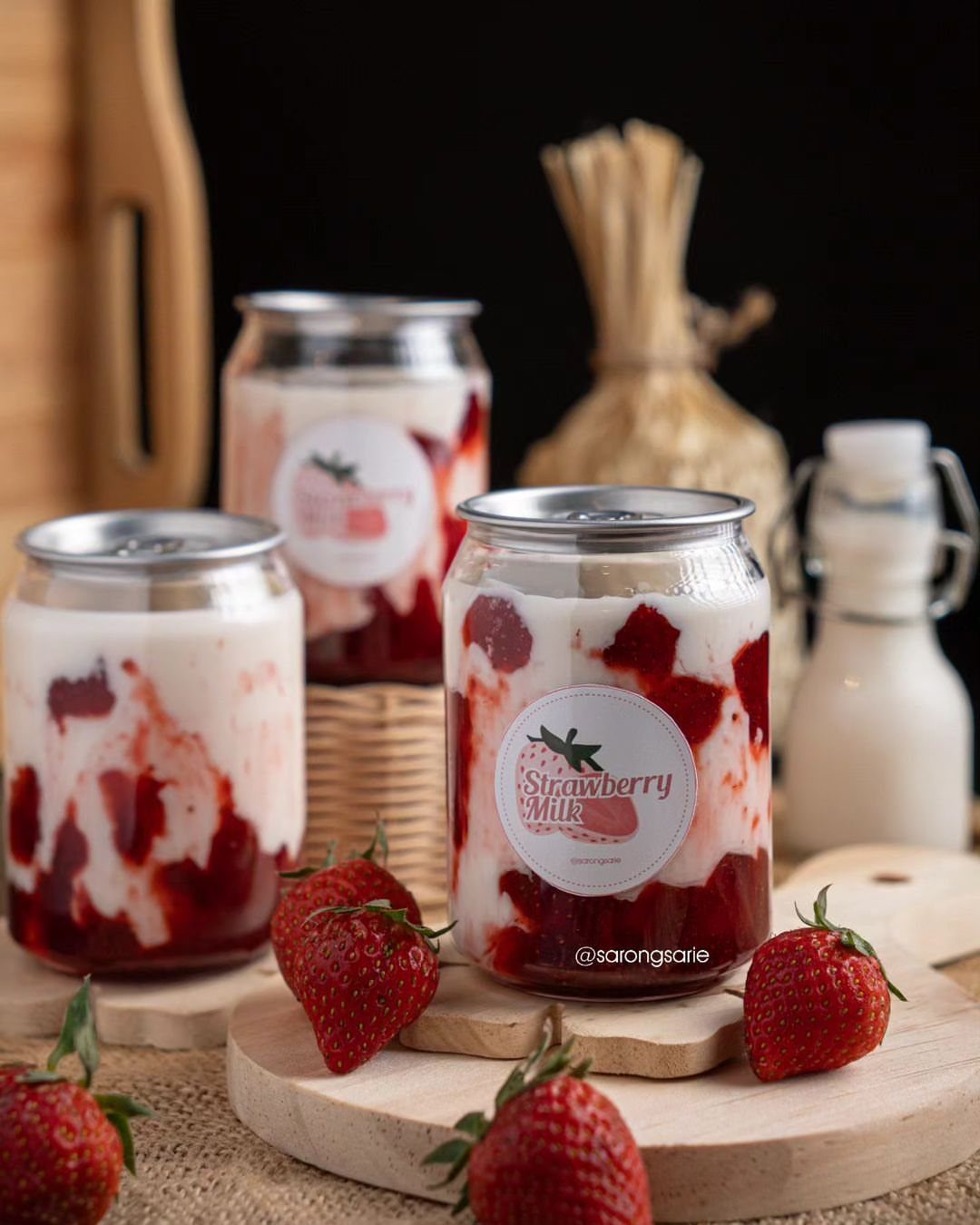 Strawberry milk in glass jars with fresh strawberries on wooden boards.