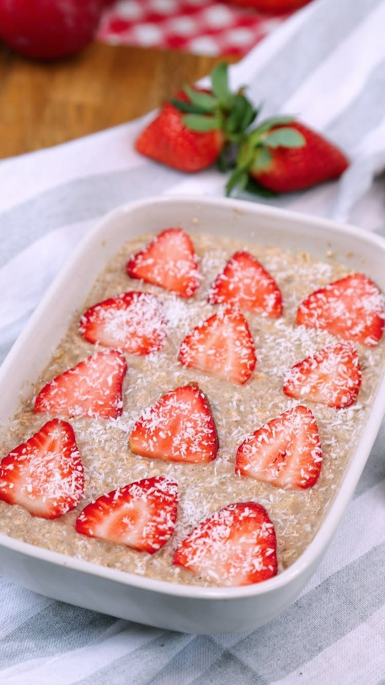 Creamy oats topped with sliced strawberries and coconut in a white dish.