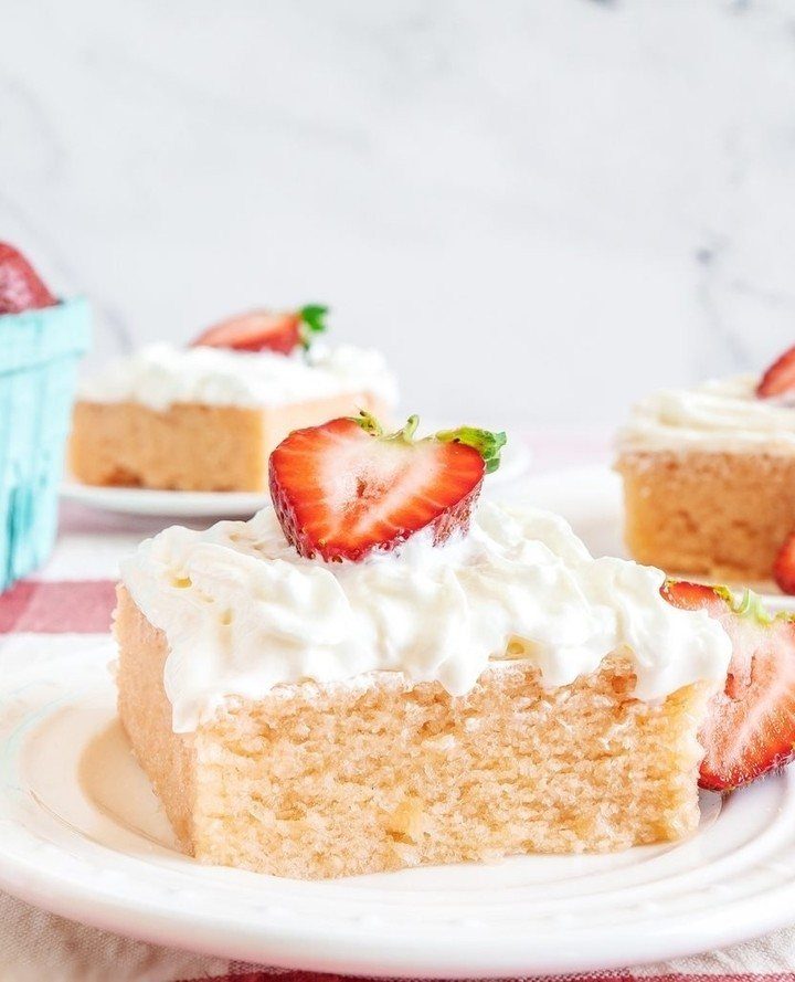 Strawberry shortcake slice with whipped cream and fresh strawberry on a white plate.