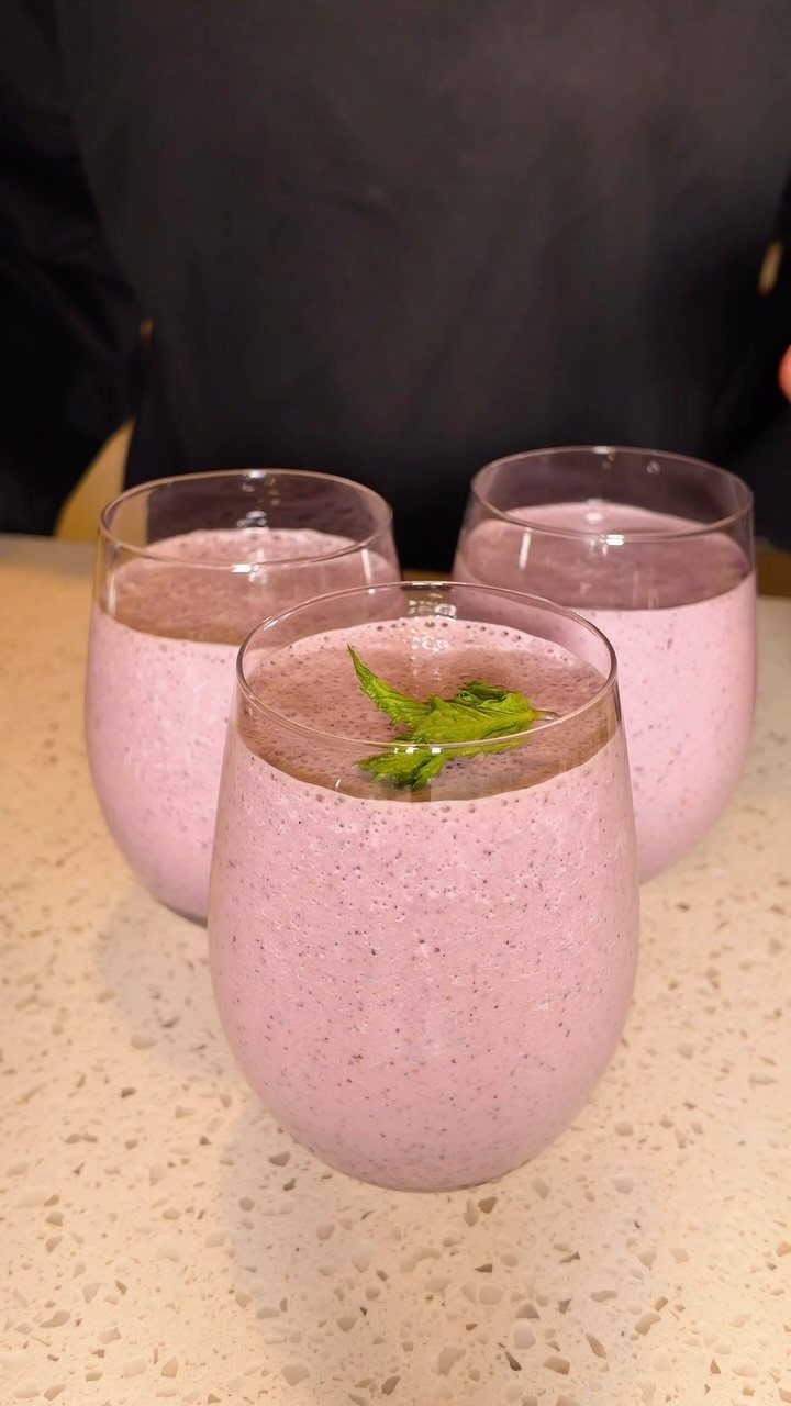 Three pink strawberry smoothies in glasses, one garnished with a fresh mint leaf.