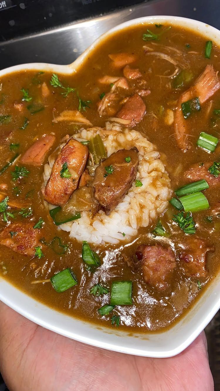 Chicken and sausage Creole stew with rice in a heart-shaped white bowl.