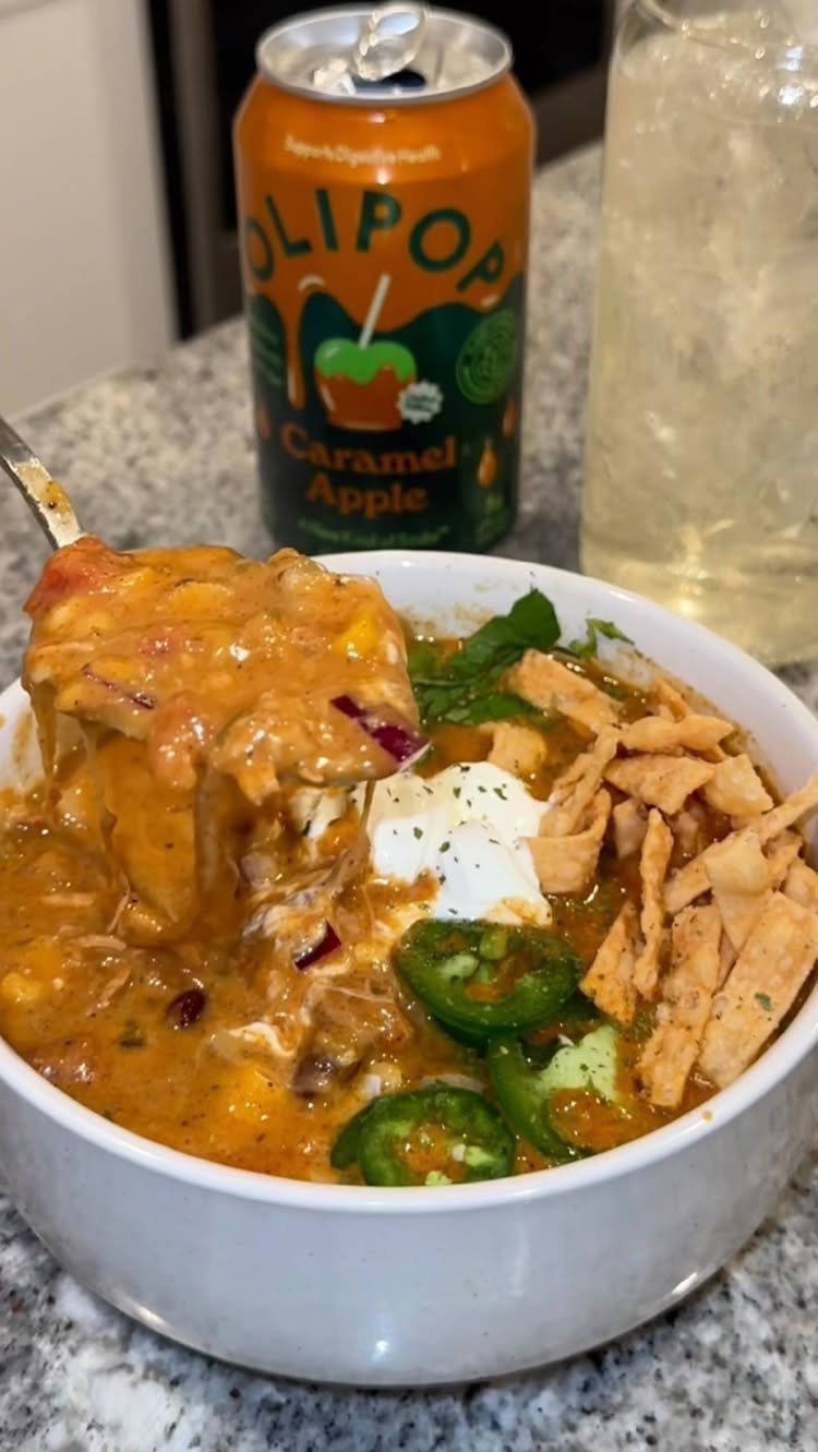 Chicken tortilla soup in a white bowl with tortilla strips and jalapeño slices.
