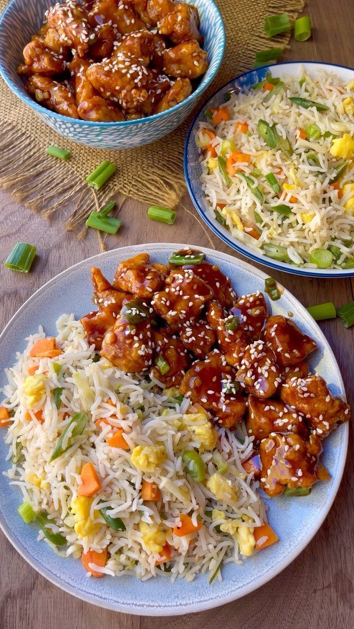 Glazed sesame chicken and vegetable fried rice served on a light blue plate.