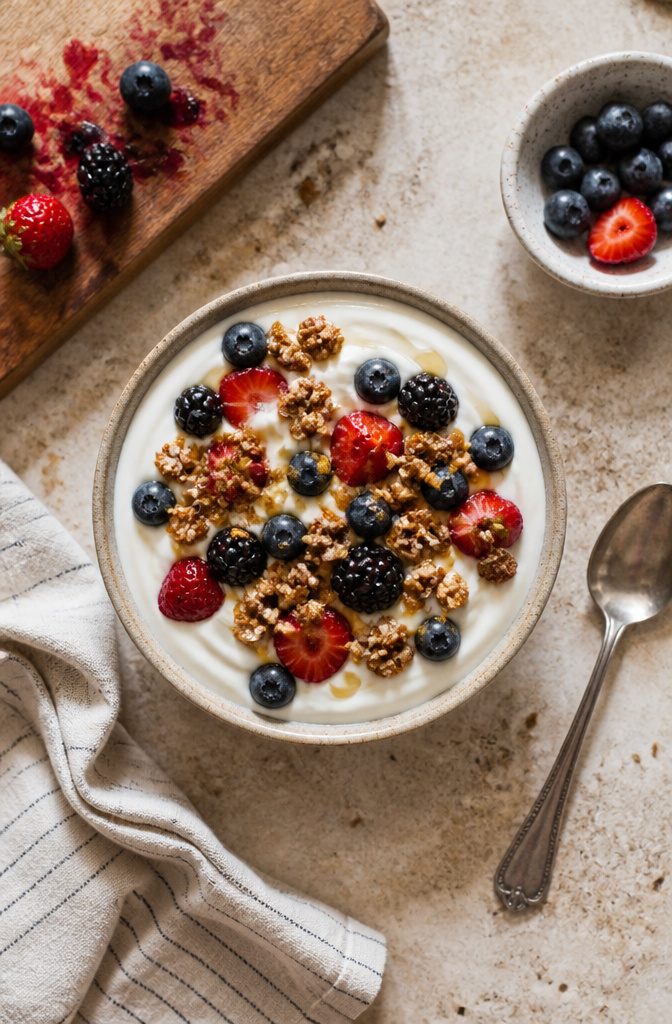 Bowl of yogurt topped with berries and granola, finished with a honey drizzle