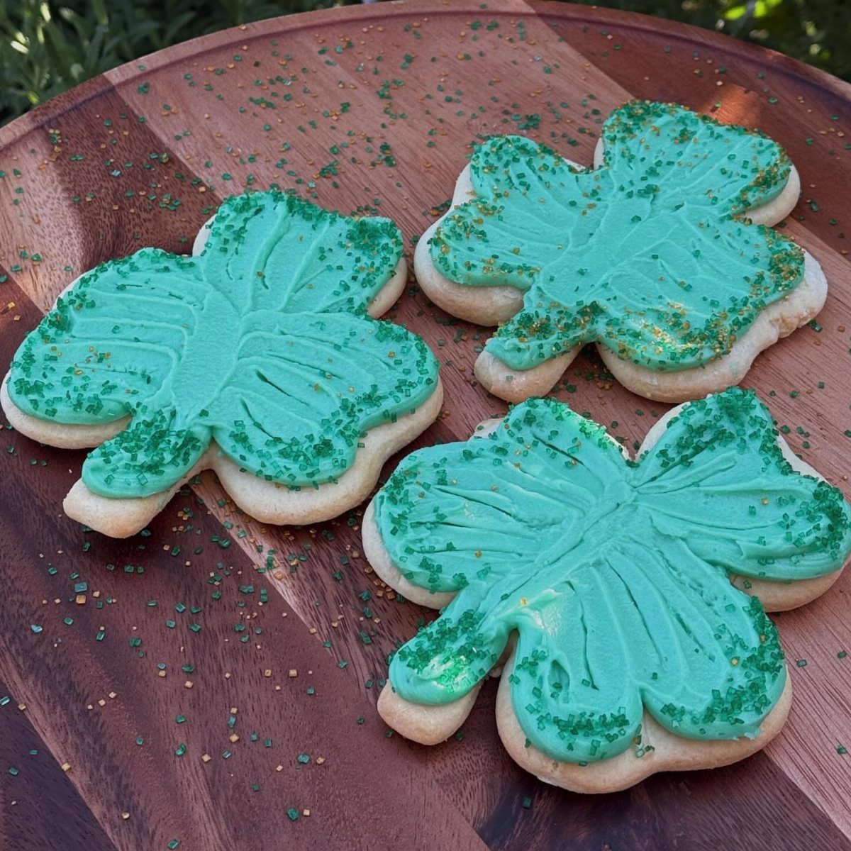 Fun Shaped Cookies: 35 Cut-Out Cookie Recipes to Decorate 25 Butterfly-shaped cookies with teal frosting and green glitter on a wooden board.