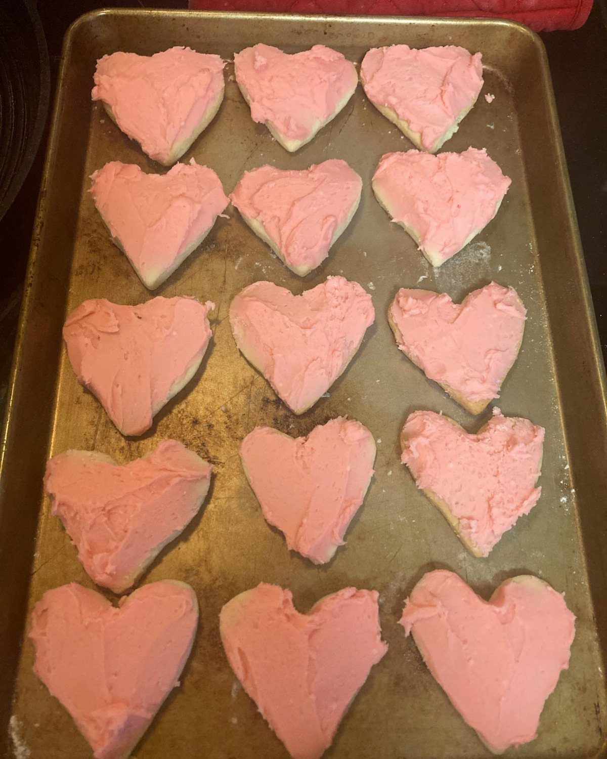 Fun Shaped Cookies: 35 Cut-Out Cookie Recipes to Decorate 32 Heart-shaped cookies with pink frosting on a metal baking sheet.