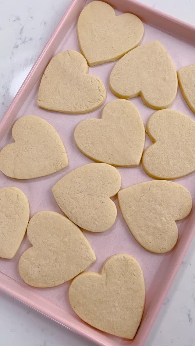 Fun Shaped Cookies: 35 Cut-Out Cookie Recipes to Decorate 33 Heart-shaped sugar cookies arranged on a pink baking tray over a white surface.