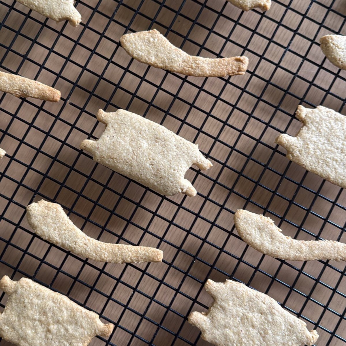 Fun Shaped Cookies: 35 Cut-Out Cookie Recipes to Decorate 23 Animal-shaped cutout cookies cooling on a black wire rack over a wooden table.