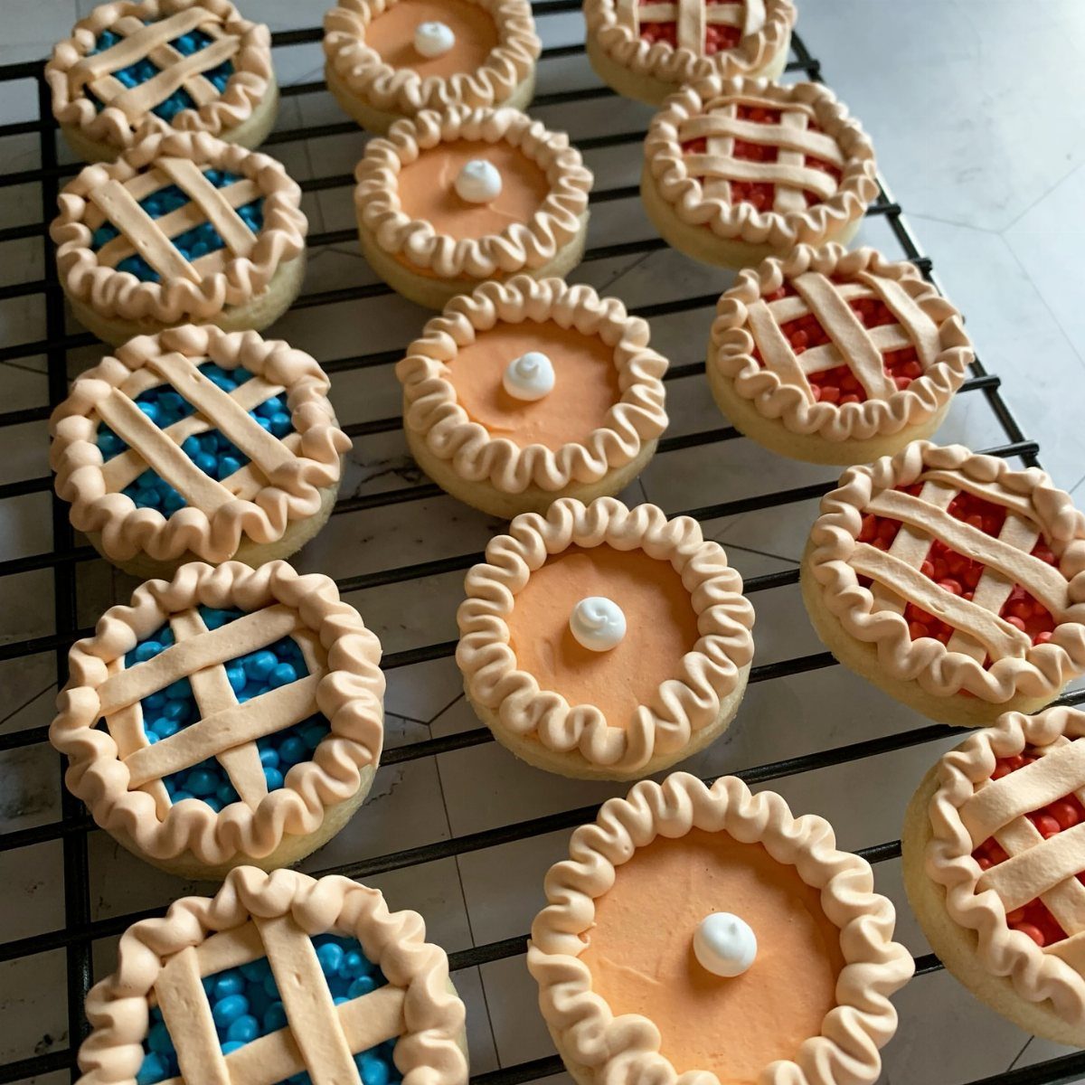 Fun Shaped Cookies: 35 Cut-Out Cookie Recipes to Decorate 29 Miniature pie shaped cookies with blue, orange, and red fillings on a cooling rack.
