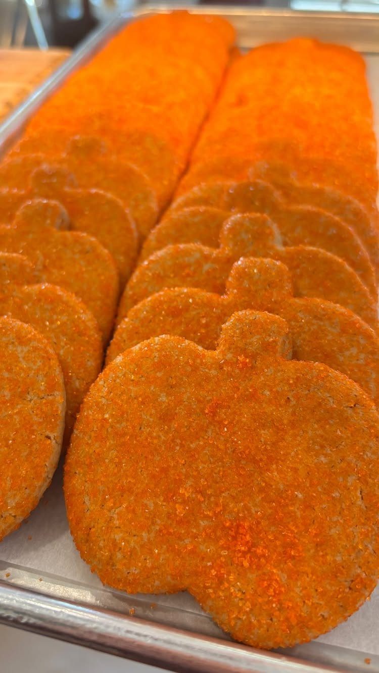 Fun Shaped Cookies: 35 Cut-Out Cookie Recipes to Decorate 14 Pumpkin shaped orange sugar cookies arranged in rows on a metal baking tray.