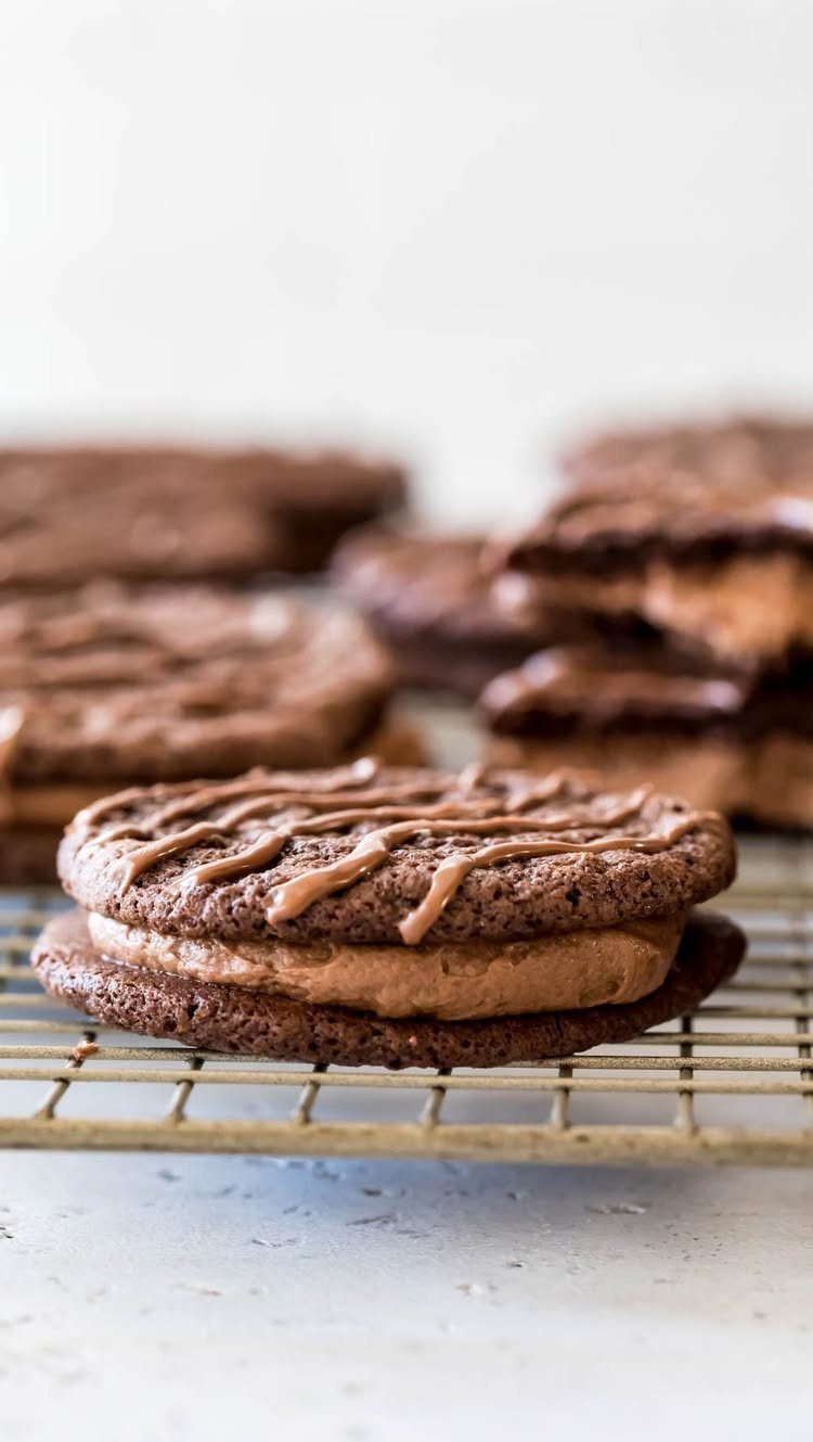 Fun Shaped Cookies: 35 Cut-Out Cookie Recipes to Decorate 22 Chocolate cookie sandwiches with fudge filling and chocolate stripes on a cooling rack.