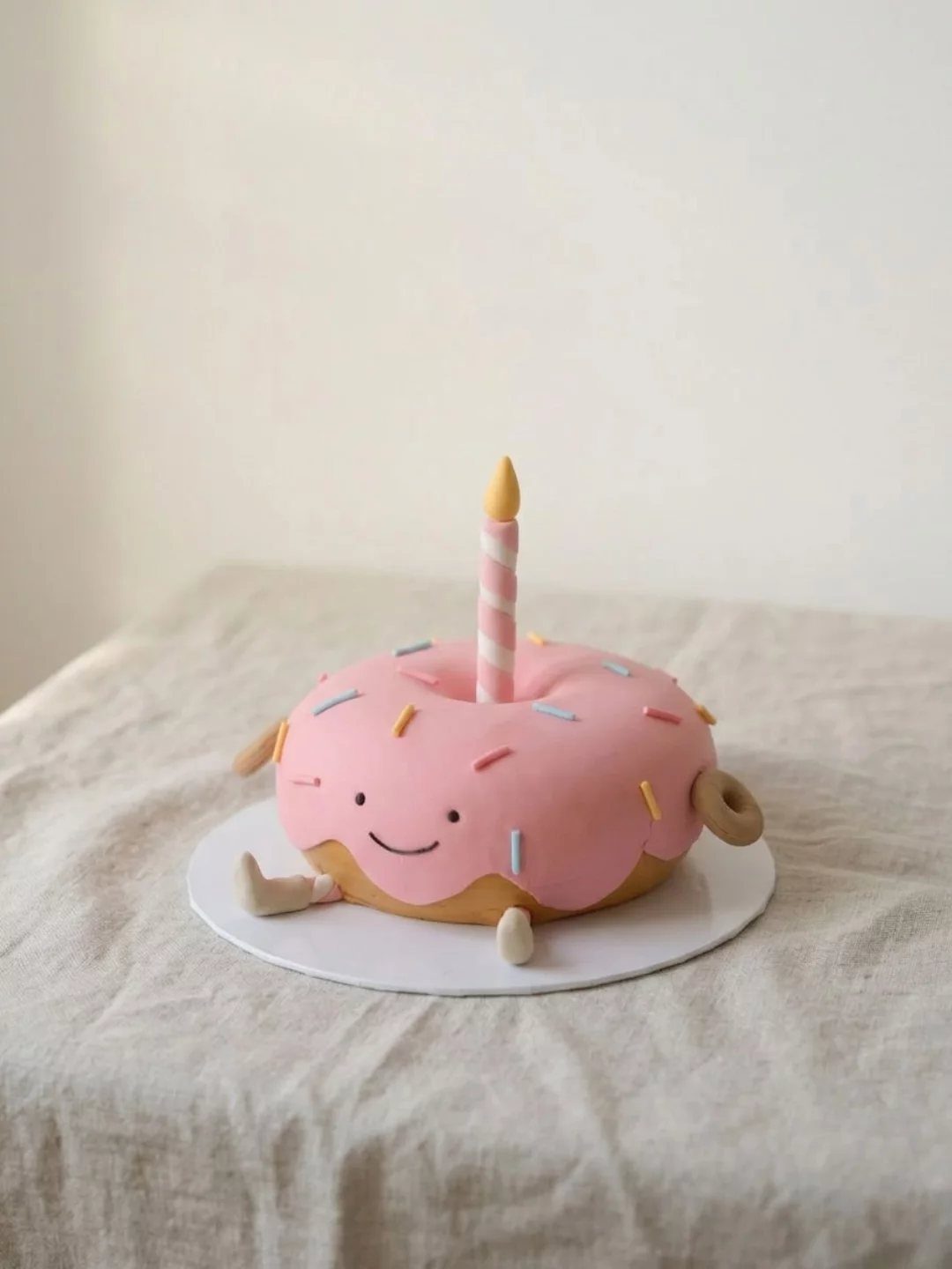 24 Funny Cakes Ideas for Birthdays, From Pizza to Poop Emoji 17 Pink frosted doughnut cake with a smiling face and a striped candle.