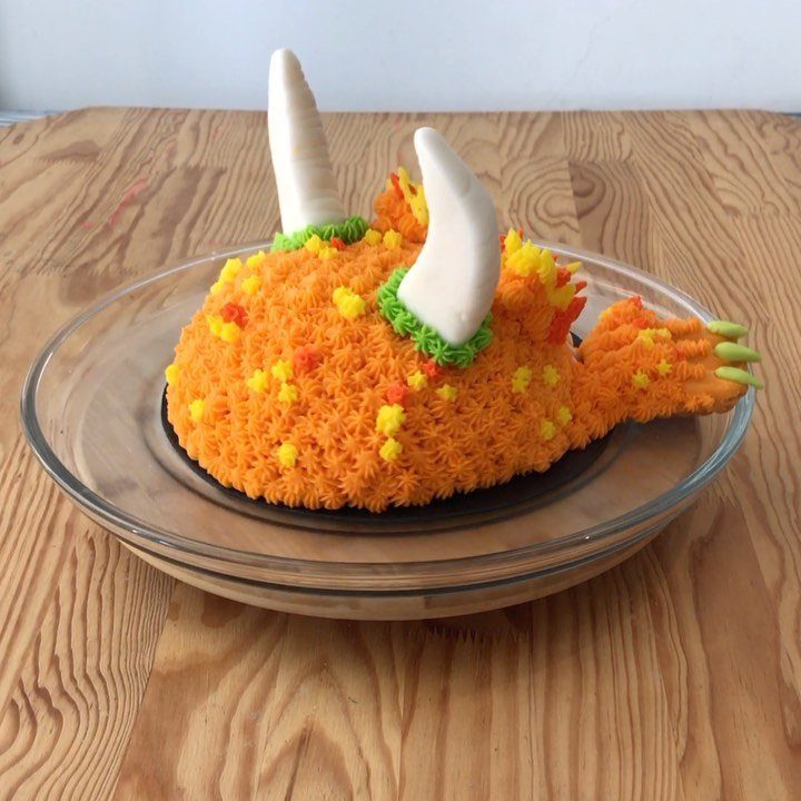 24 Funny Cakes Ideas for Birthdays, From Pizza to Poop Emoji 25 Orange monster cake with white horns and a tail on a glass plate.