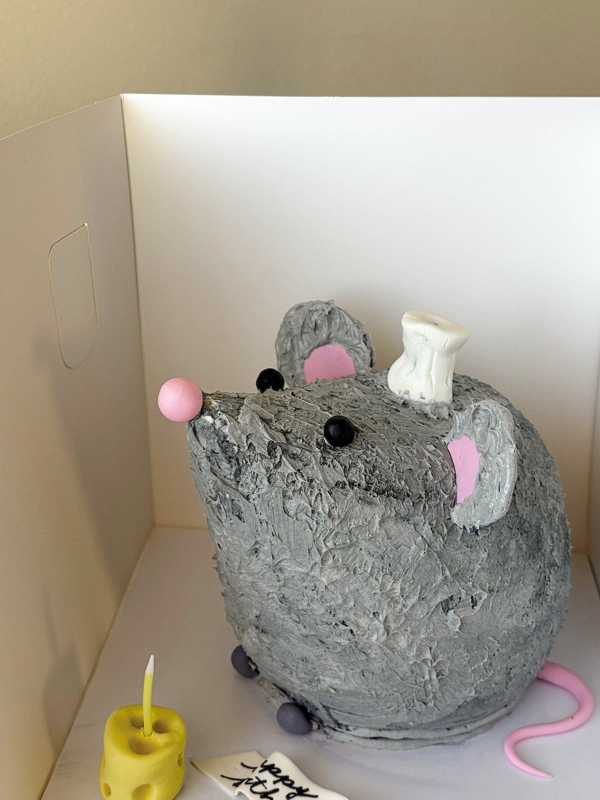 24 Funny Cakes Ideas for Birthdays, From Pizza to Poop Emoji 13 Grey mouse-shaped cake with a pink nose and a small white chef hat.