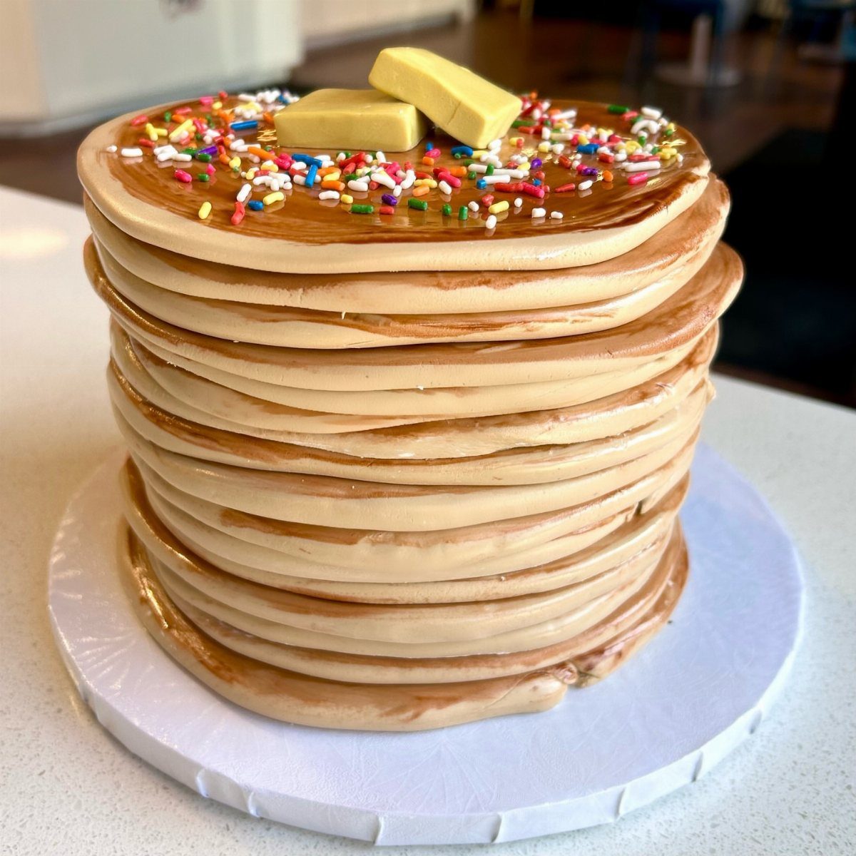 24 Funny Cakes Ideas for Birthdays, From Pizza to Poop Emoji 5 Pancake stack cake with brown syrup, colorful sprinkles, and yellow fondant butter squares.