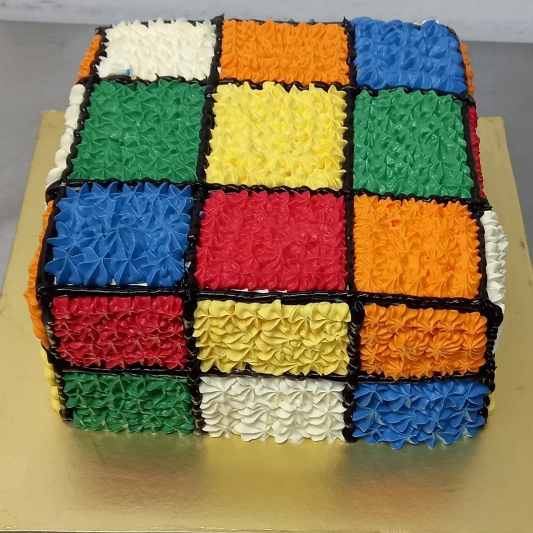 24 Funny Cakes Ideas for Birthdays, From Pizza to Poop Emoji 7 Rubik's Cube cake with colorful piped frosting squares on a gold board