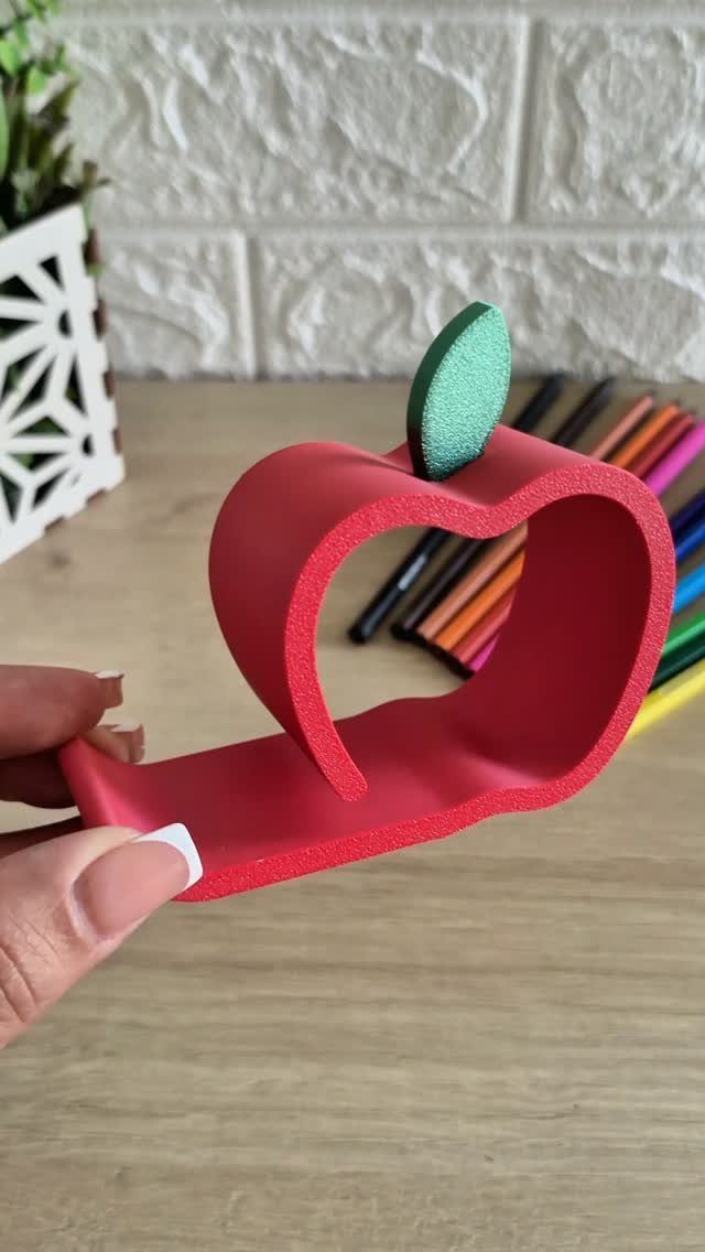 38 Gift Ideas for 13th Birthday in 2026, From Snoopy to LEGO 27 Red apple-shaped phone stand with a green leaf held by a hand.