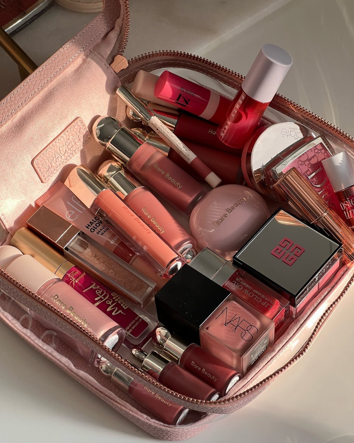 38 Gift Ideas for 13th Birthday in 2026, From Snoopy to LEGO 14 Pink flat lay makeup bag filled with various lip glosses and cosmetic products.