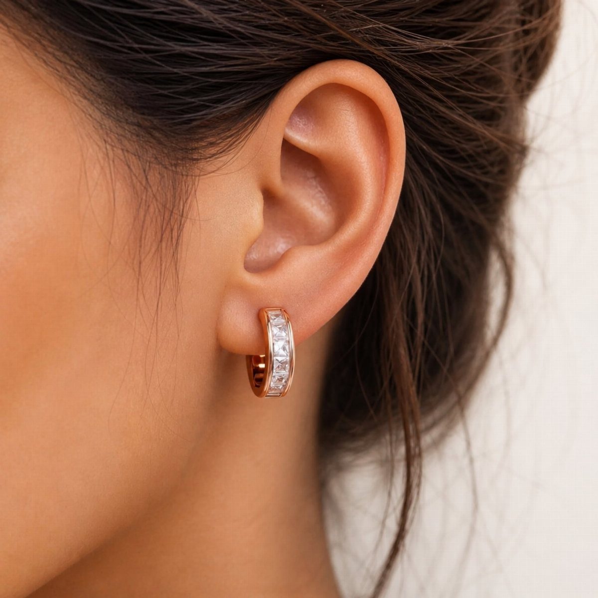 38 Gift Ideas for 13th Birthday in 2026, From Snoopy to LEGO 6 Rose gold huggie hoop earrings with clear crystals worn on a person's ear.