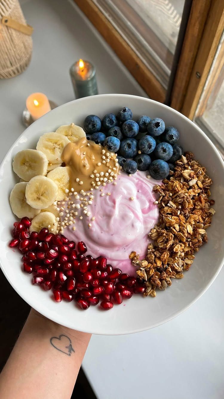 Yogurt bowl with blueberries, bananas, pomegranate seeds, granola, and peanut butter.