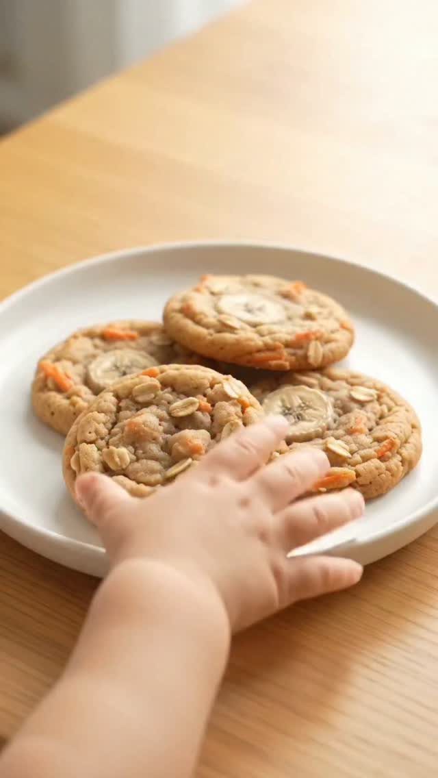 Oatmeal cookies with banana slices on a white plate with a child's hand.