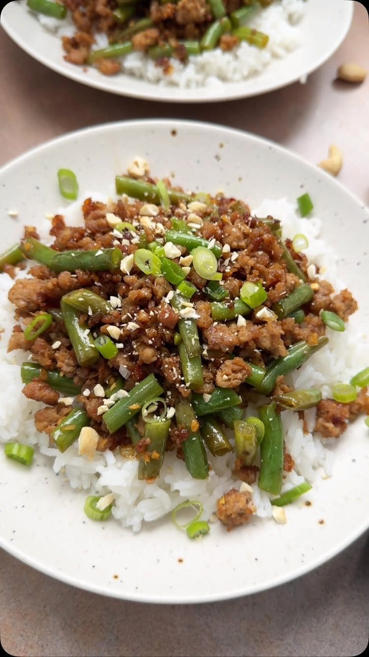 Ground pork and green bean stir-fry served over a bed of white rice.
