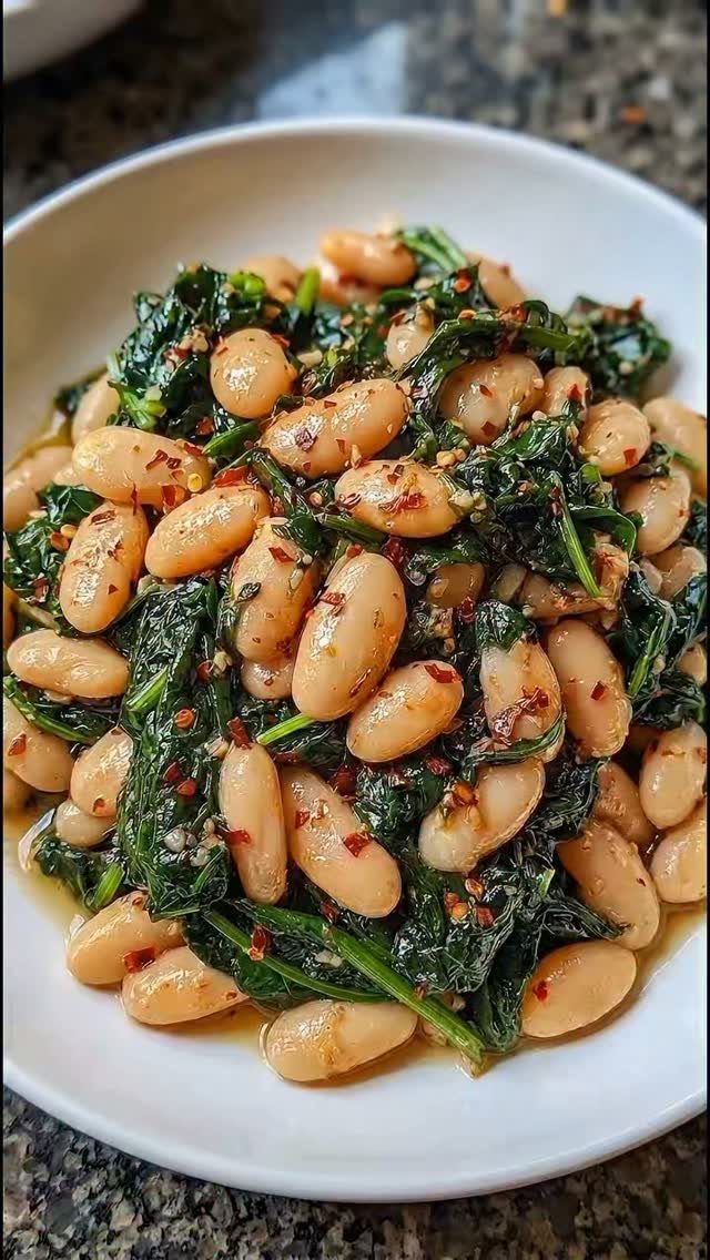 White beans and sautéed kale with red pepper flakes in a white bowl